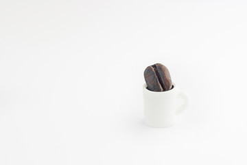 Miniautre white coffee cup with a coffee bean inside isolated on a white background