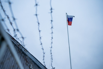 Metal fence with barbed wire on a russian flag