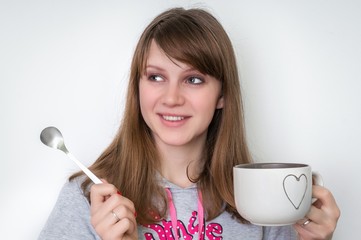 Young beautiful woman with spoon and cup of tea in hands