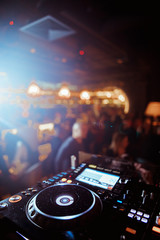 Club DJ playing mixing music on vinyl turntable at party wearing sunglasses with lens flare from...