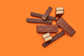 Chocolate waffle wafer desserts and bars on vibrant orange background top view. Copy space poster