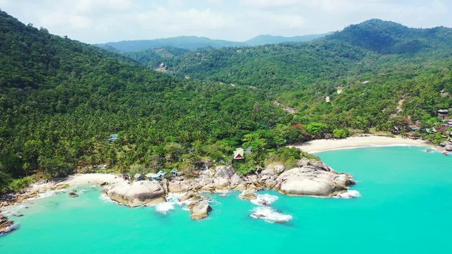Peaceful sea panorama with turquoise lagoon and white waves splashing on cliffs and sandy beach of tropical island. Koh Phangan, Thailand
