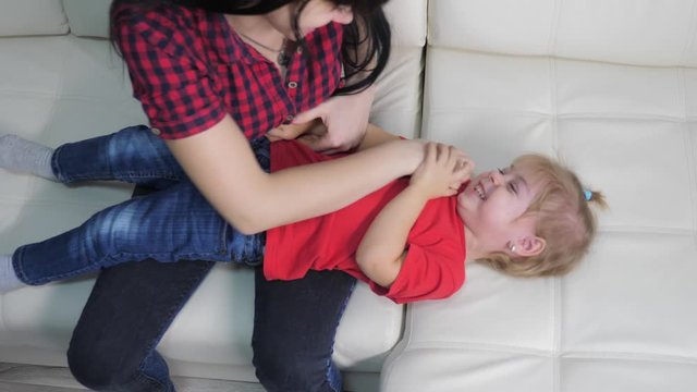 happy family little girl laughs lifestyle from tickling. woman playing with daughter indoors a happy family laughing
