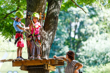 adventure climbing high wire park - children on course rope park in mountain helmet and safety equipment