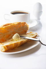 Breakfast. Croissant with butter, coffee and soft-boiled egg. High key. Selective focus.