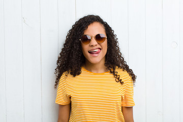 young latin woman with cheerful, carefree, rebellious attitude, joking and sticking tongue out,...
