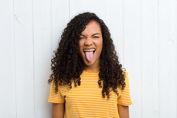 young latin woman with cheerful, carefree, rebellious attitude, joking and sticking tongue out,...