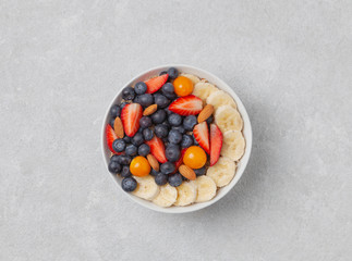 Delicious summer Breakfast. Smoothie bowl with muesli, banana, strawberries, blueberries, physalis, almonds and yogurt.