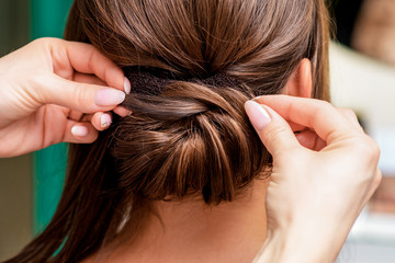 Hairdresser makes hairstyle for woman in beauty salon, close up, back view.