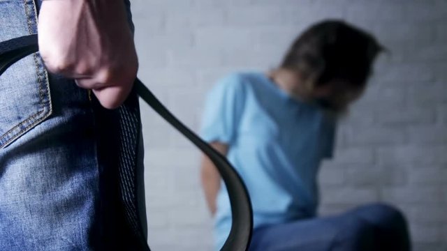 Man holding belt in hands, woman afraid of aggressive husband - domestic violence, abuse and people concept