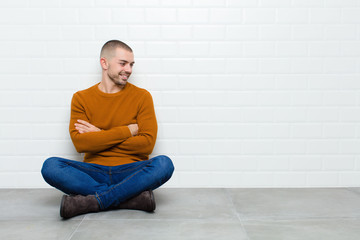 young handsome man smiling with a happy, confident expression with hand on chin, wondering and...