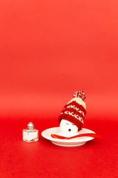 Fun breakfast concept with a boiled egg with abstract sleepy human face wearing a knitted woolen hat on red background.