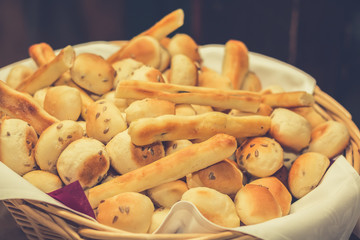 A bunch of small pastries in wicker basket at the restaurant table ready for self serve. Close up.