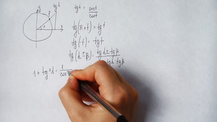 student writes trigonometric formulas on paper	