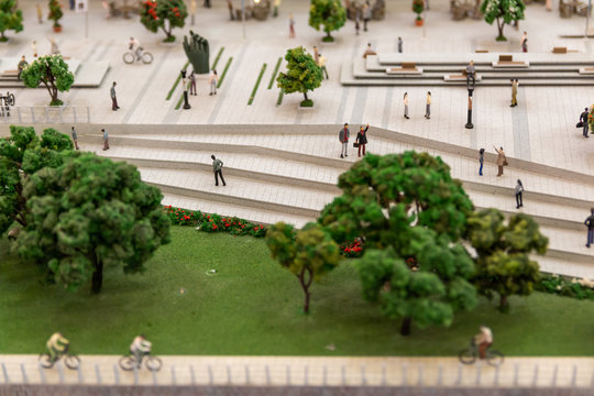 Miniature people figurines at modern city square.