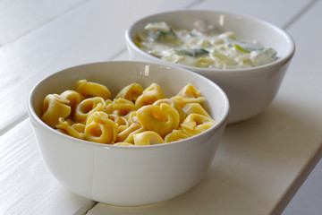 Cooked tortellini and vegetarian sauce in white bowls. Sauce made with leek, zucchini, mushroom, onion, herb butter, creme fresh