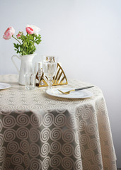 photo of a festively served table, the corner of the table with a plate is cropped. light dishes and a tablecloth.