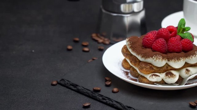 portion of tiramisu dessert with raspberries, espresso and coffee maker on concrete background