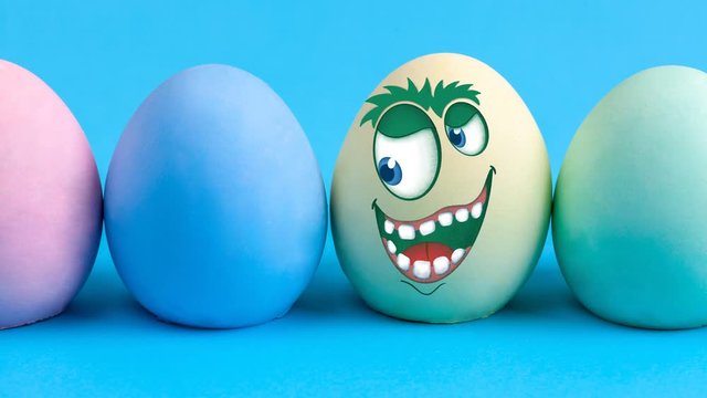 Cute and happy monster face with blinking eyes drawn on colorful Easter egg animation - seamless loop