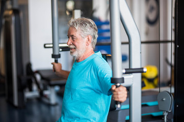 close up of mature man at the gym doing exercise alone lifting weight to build his body and be fit...