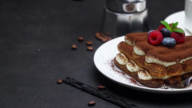 tiramisu dessert with raspberries and blueberries, espresso and coffee maker on concrete background