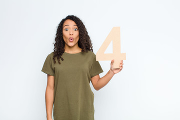 young black woman surprised, shocked, amazed, holding a number 4.
