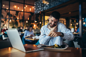 young businessman having lunch and using laptop in restaurant
