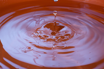 Water drop falling and drips in colored glass. Water drop splash and make perfect circles and...