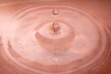 Water drop falling and drips in colored glass. Water drop splash and make perfect circles and...