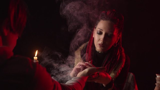 Fortune teller reading palm and predicting future in smoke
