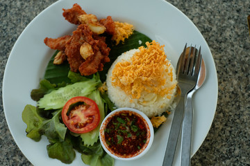 Fried pork,vegetable,fired egg on top of steamed rice on white plate 1