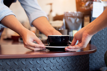 Fototapeta na wymiar Close up barista hand serving coffee cup to customer.