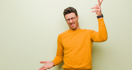young arabian man shrugging with a dumb, crazy, confused, puzzled expression, feeling annoyed and...
