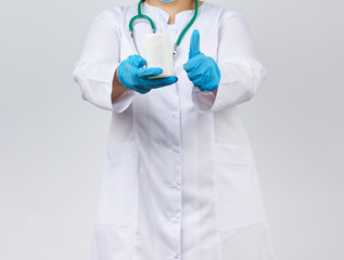 woman physician in a white coat and mask holding a white plastic jar for the medicines and tablets