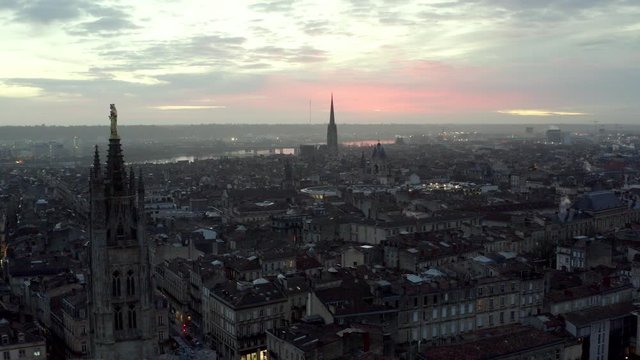 Pey Berland bell tower on St. Andrew Cathedral at sunset with Basilica of Saint Michael far in the distance, Bordeaux France, Aerial drone flyover shot