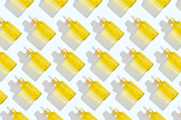 pattern of dropper bottles with white pipette and yellow liquid on white background