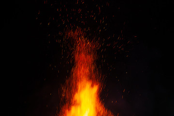 Fototapeta na wymiar Fire flames on a dark background with lots of fiery sparks from a blazing fire