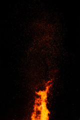 Fire flames on a dark background with lots of fiery sparks from a blazing fire