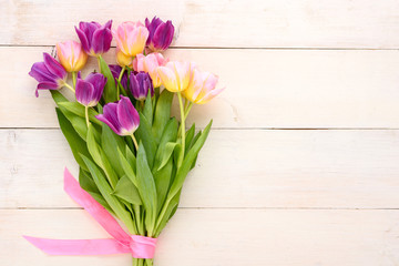 spring Tulip bouquet with pink bow on light wooden background