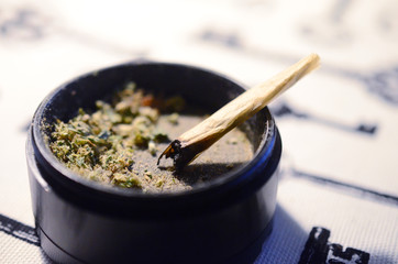 Marijuana joint and grinder. Ground cannabis and joint. THC and CBD for healing. Macro photo of hemp joint and flower, beautiful natural healing alternatives. 