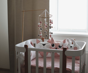 Beautiful interior of baby room with a crib. White crib with pillows and pink blanket in baby room. pastel pink bedding 
