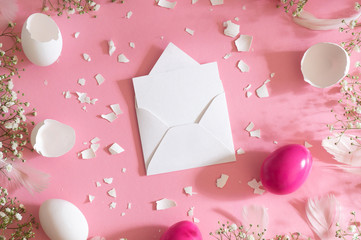 Blank greeting card, kraft envelope. Easter eggs and gypsophila flowers on a pink background