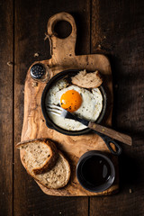 Fototapeta na wymiar Fried egg, bread slice and black coffee.Chopping board. Dark, wooden, rustick table. Overhead view.