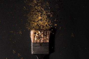 black brush covered with gold paint with gold stars on black background