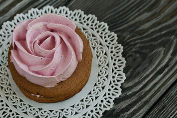 Marshmallows sandwiches made from chocolate dough and blueberry marshmallows. In the form of a rose. On a lace napkin, on brushed pine boards. Close-up shot.