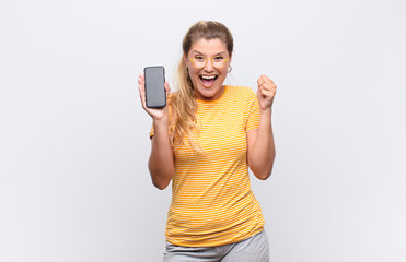 young pretty latin woman feeling shocked, excited and happy, laughing and celebrating success,...