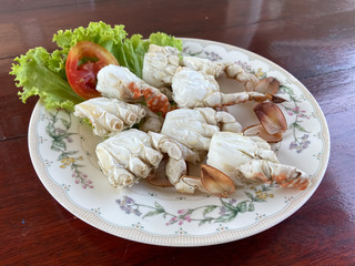 Close up of delicious steamed crab meat lumps serves on a white plate placing on wooden table background. 