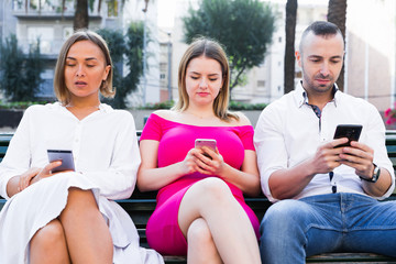 Young people are focusing on smartphones during a together walking