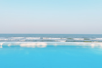 Fresh cool blue pool and ocean waves with infinite view of clear sky background with ray of sunshine, with copy space.