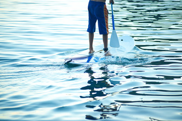 Stand Up Paddling in the sea. SUP. Guy Training in the morning on Paddle Board near the rocks.